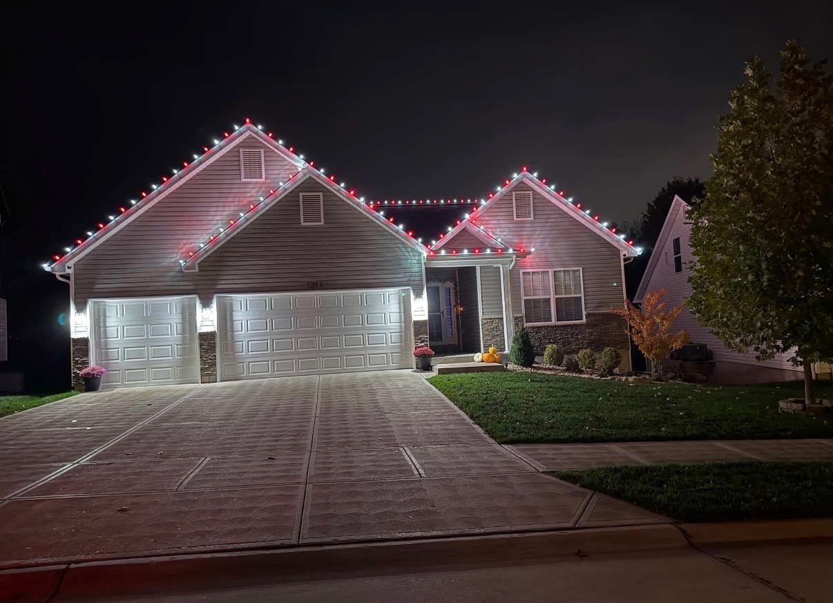 A home outlined with red and white holiday lights at night